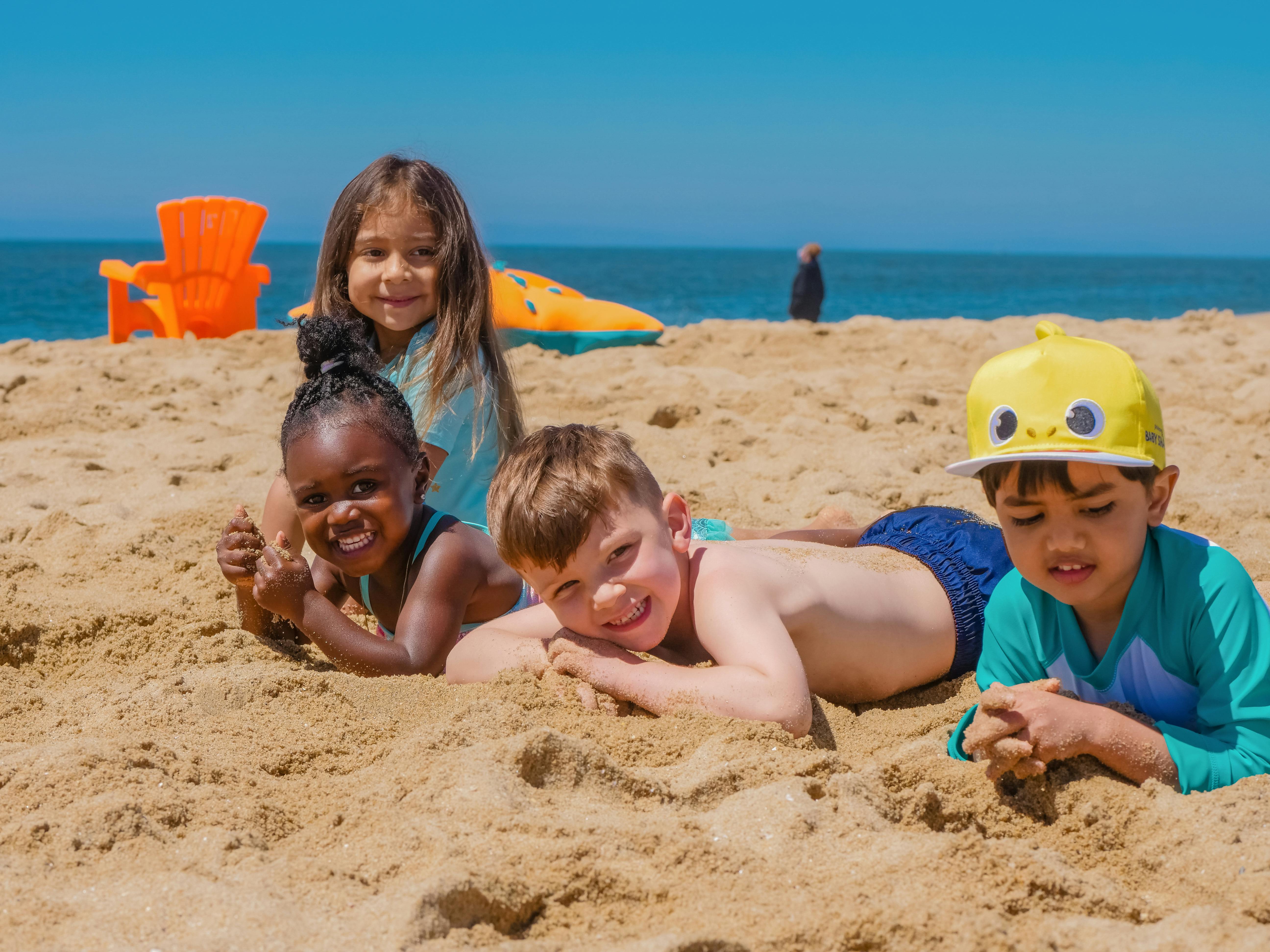 Vier kinderen spelen lachend in het zand op het strand